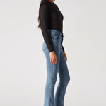 Side profile walking shot highlighting the bootcut leg of mid blue jeans