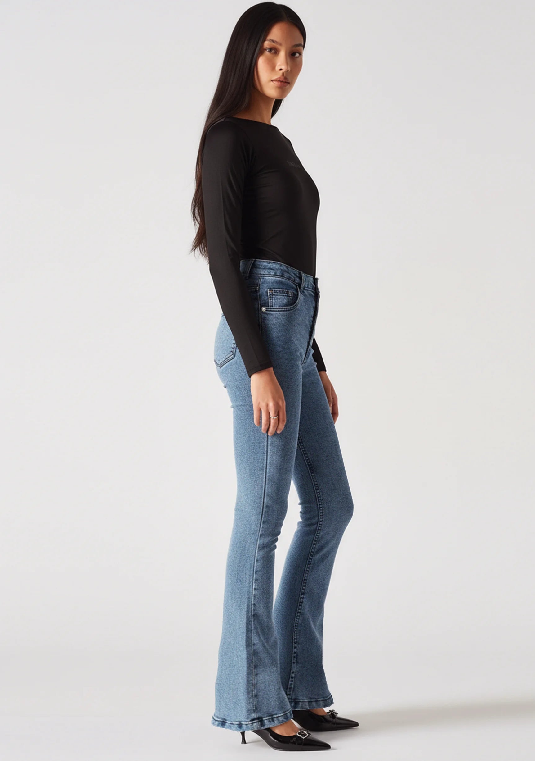 Side profile walking shot highlighting the bootcut leg of mid blue jeans