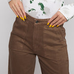 Angled close up view of the high waist fit on brown carpenter style pants