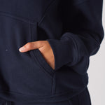 Close up of a hand in the front pocket of a navy hoodie womens top