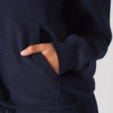 Close up of a hand in the front pocket of a navy hoodie womens top