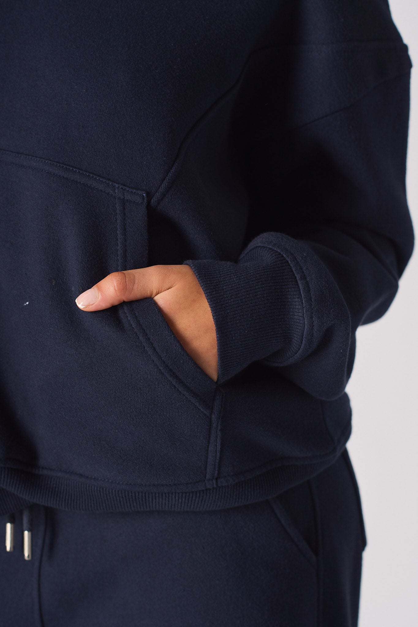 Close up of a hand in the front pocket of a navy hoodie womens top