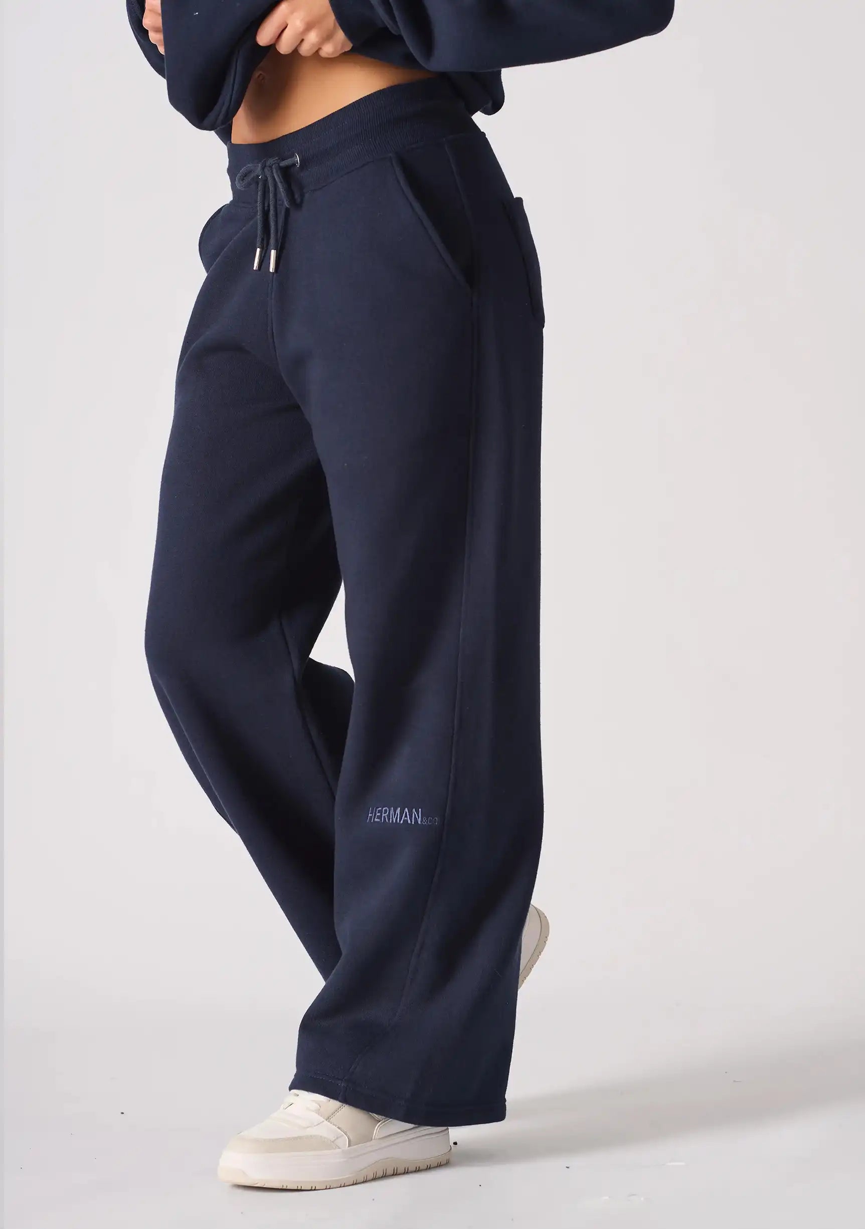 Side view of a woman wearing navy wide leg joggers showing the relaxed fit