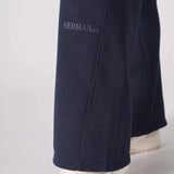 Close up of the tonal embroidered logo on the bottom of the navy wide leg joggers