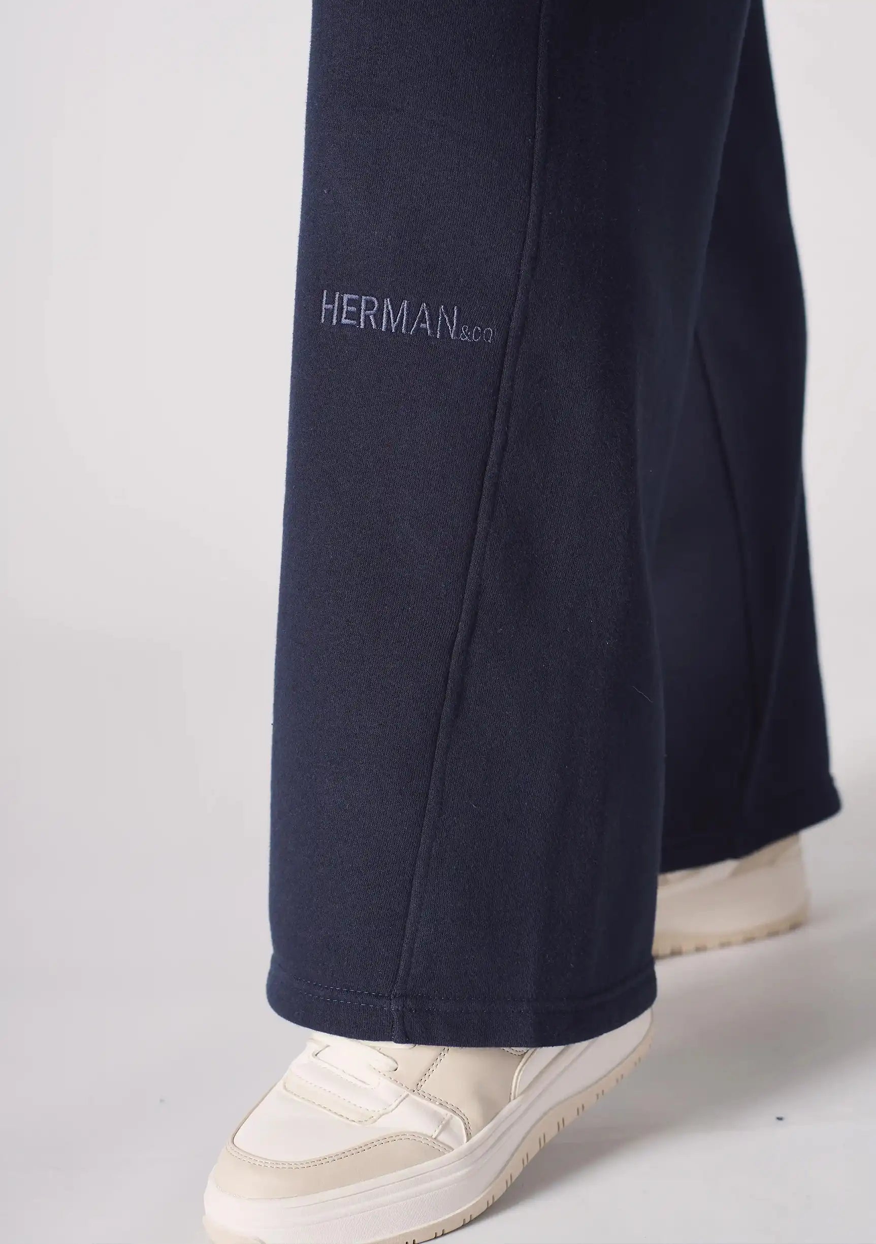 Close up of the tonal embroidered logo on the bottom of the navy wide leg joggers