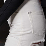 Side view showing the hip and distressed details on the off-white jeans.