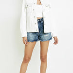 Front view of oversized white denim jacket with contrast stitching worn open - women's relaxed cotton trucker jacket with white crop top and distressed denim shorts