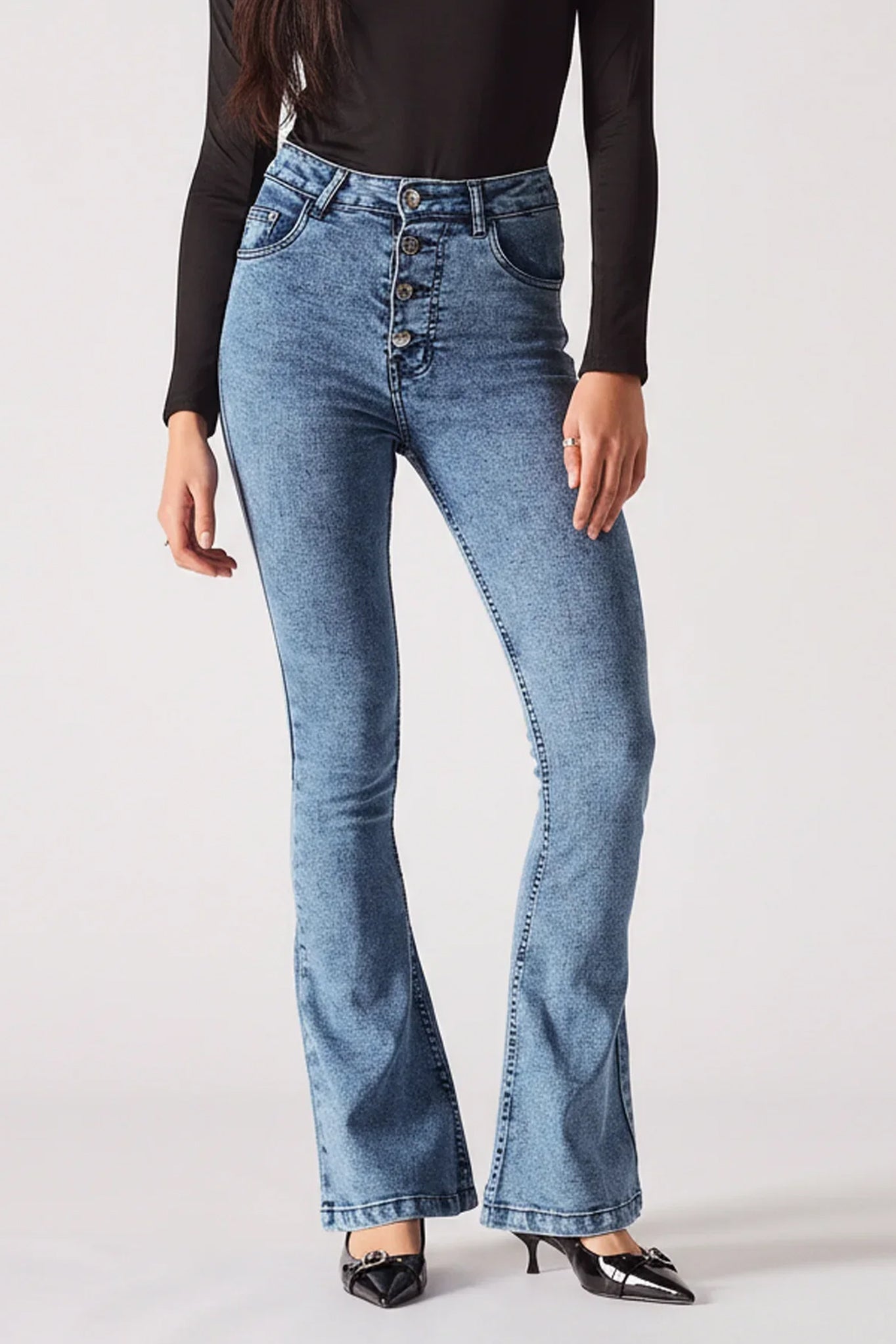 Person wearing blue flared jeans on a white background