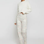 Model casually leaning against a wall with one hand in her pocket wearing psychedelic marble tapered trousers.
