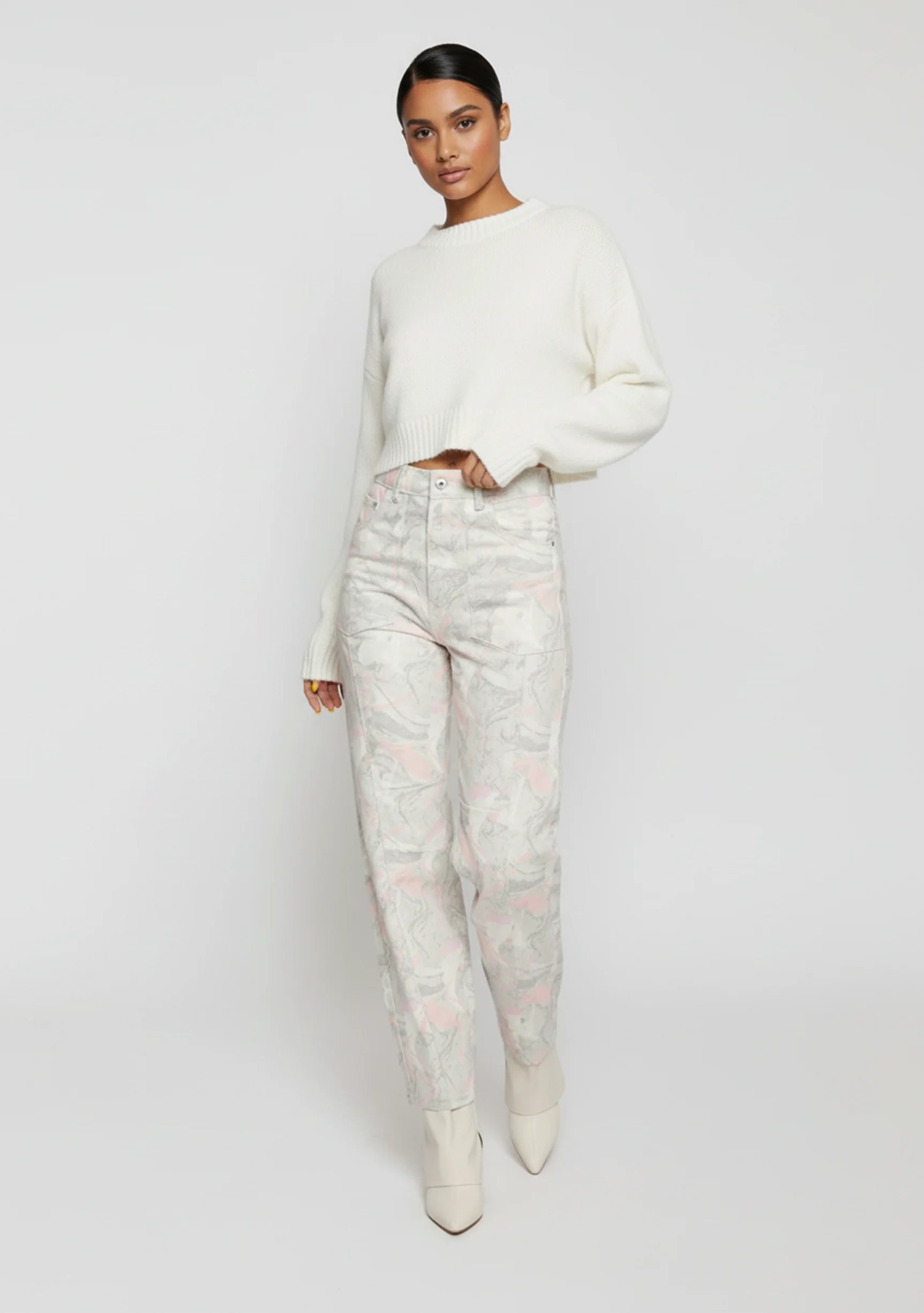 Model casually leaning against a wall with one hand in her pocket wearing psychedelic marble tapered trousers.
