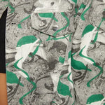 Close up of psychedelic print denim jacket chest pocket with silver button - showcasing green-grey-white abstract swirl fabric texture and collar detail