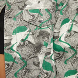 Close up of psychedelic print denim jacket chest pocket with silver button - showcasing green-grey-white abstract swirl fabric texture and collar detail