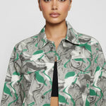 Upper body close up of psychedelic print denim jacket showing collar, placket, and chest pockets - women’s oversized abstract swirl patterned jacket over ribbed black top