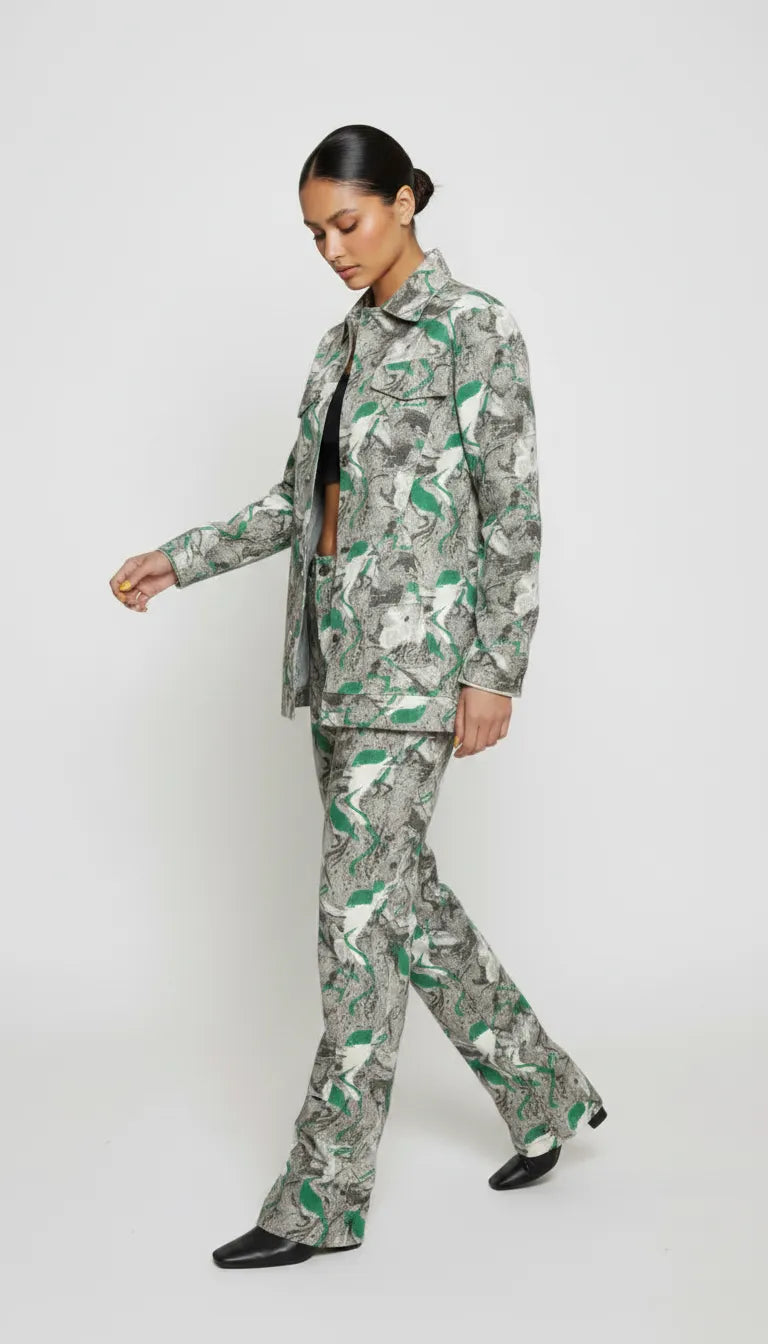 Side walking pose of psychedelic print denim jacket in motion - women’s green-grey abstract swirl patterned set with flared hem pants