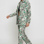 Side walking pose of psychedelic print denim jacket in motion - women’s green-grey abstract swirl patterned set with flared hem pants