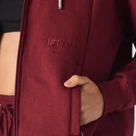 Close up detail of the tonal embroidery and pocket on the red zip up hoodie womens.