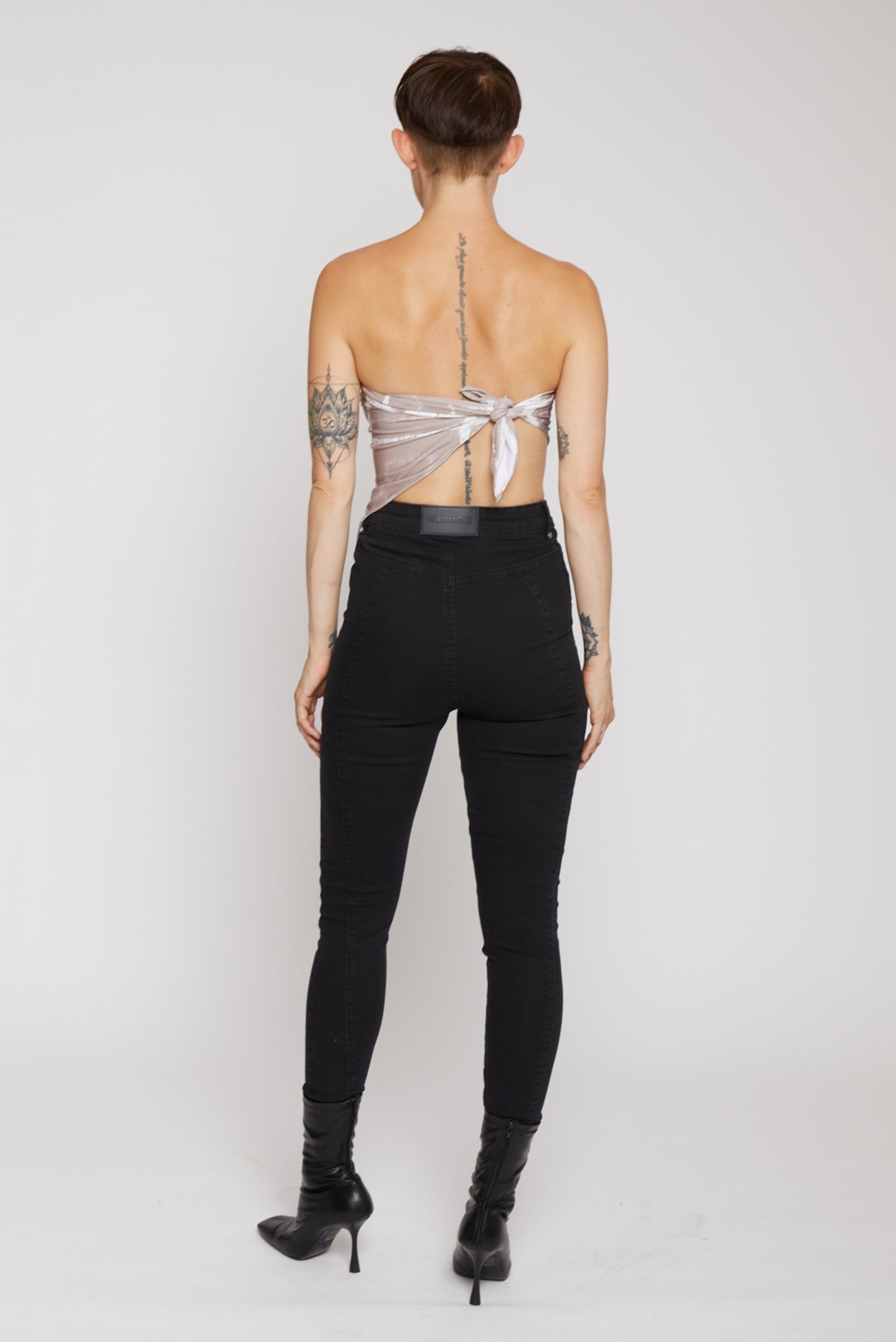 Person wearing a sheer top and black pants on a white background