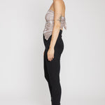 Person wearing a sheer top and black pants with high heels on a white background