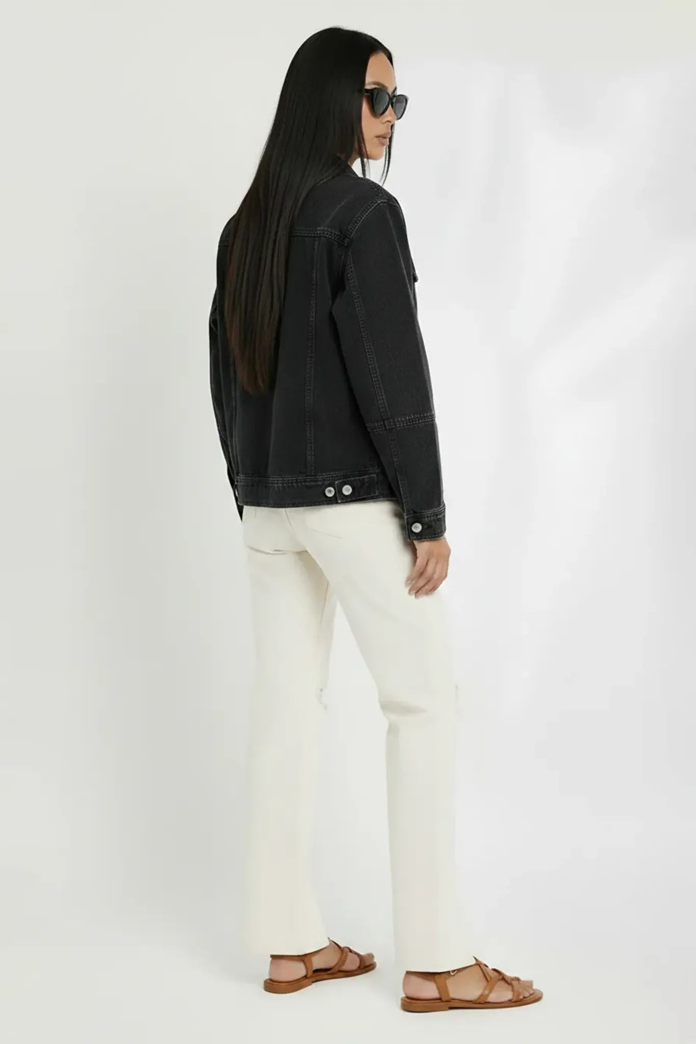 Side and back view of soft black wash denim trucker jacket for women - vintage washed cotton jacket with white pants styling