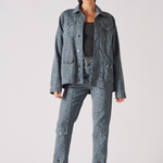 Front pose of speckle print denim jacket worn open with hands in pockets - women’s oversized acid wash set with chain belt and split-hem cargo pants