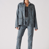 Front pose of speckle print denim jacket worn open with hands in pockets - women’s oversized acid wash set with chain belt and split-hem cargo pants