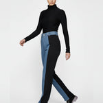 Studio shot of a model with folded arms showcasing spliced color high-rise jeans.