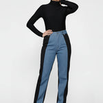 Model holding the waist of split color block jeans for women, highlighting the high-rise fit.