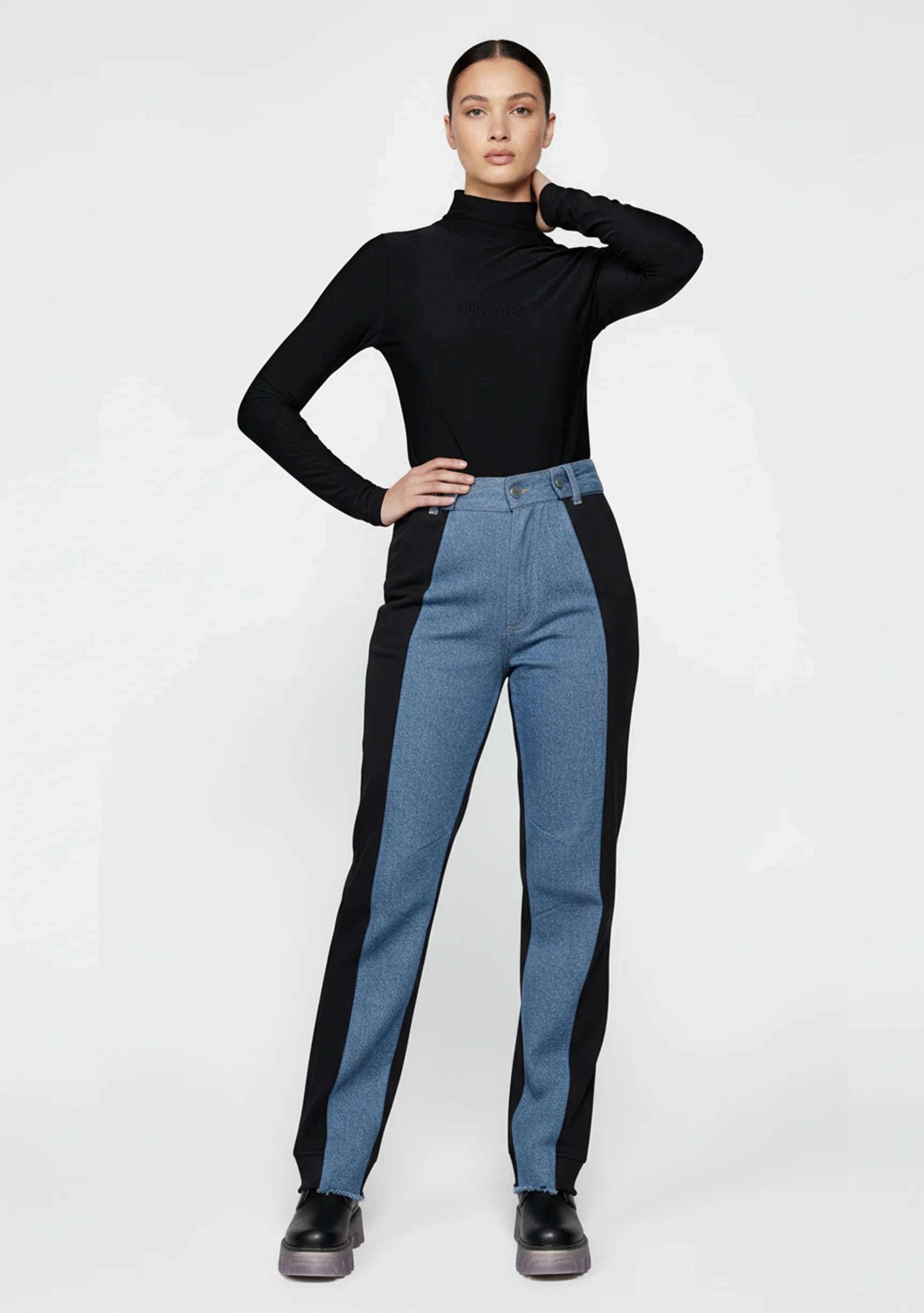 Model holding the waist of split color block jeans for women, highlighting the high-rise fit.