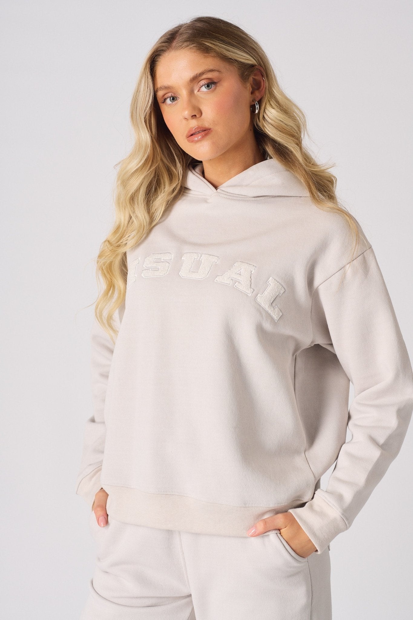 Front view of a model posing in a stone graphic hoodie with hands in pockets