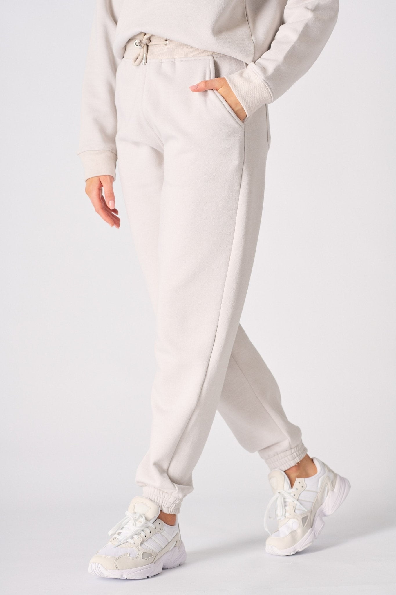 Side view of a woman walking in stone joggers and white trainers