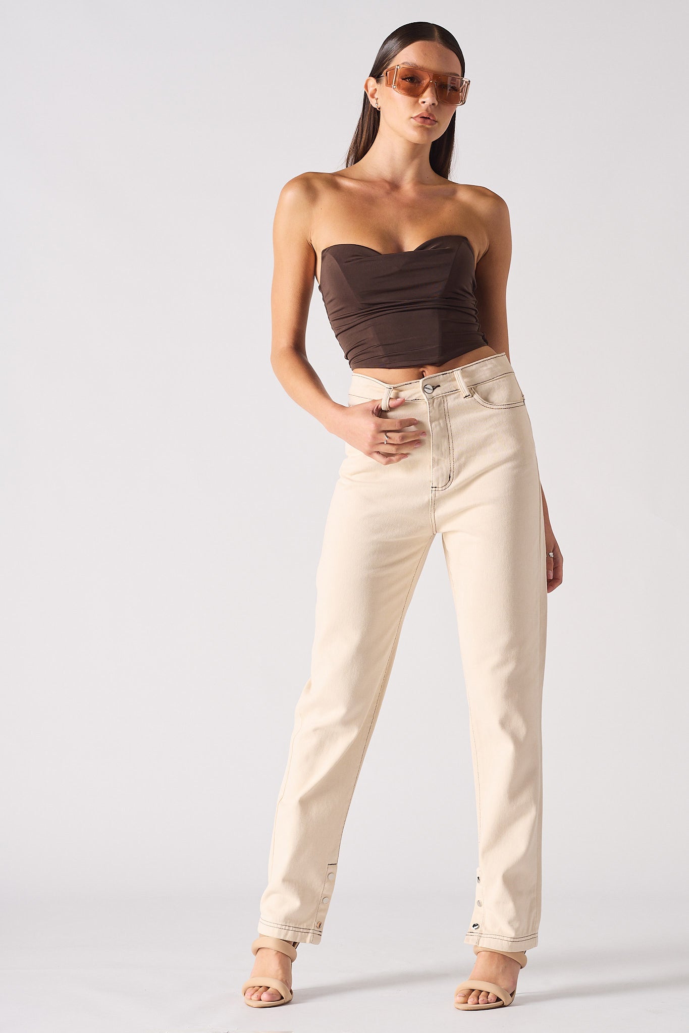 Woman wearing a strapless top and beige pants on a white background