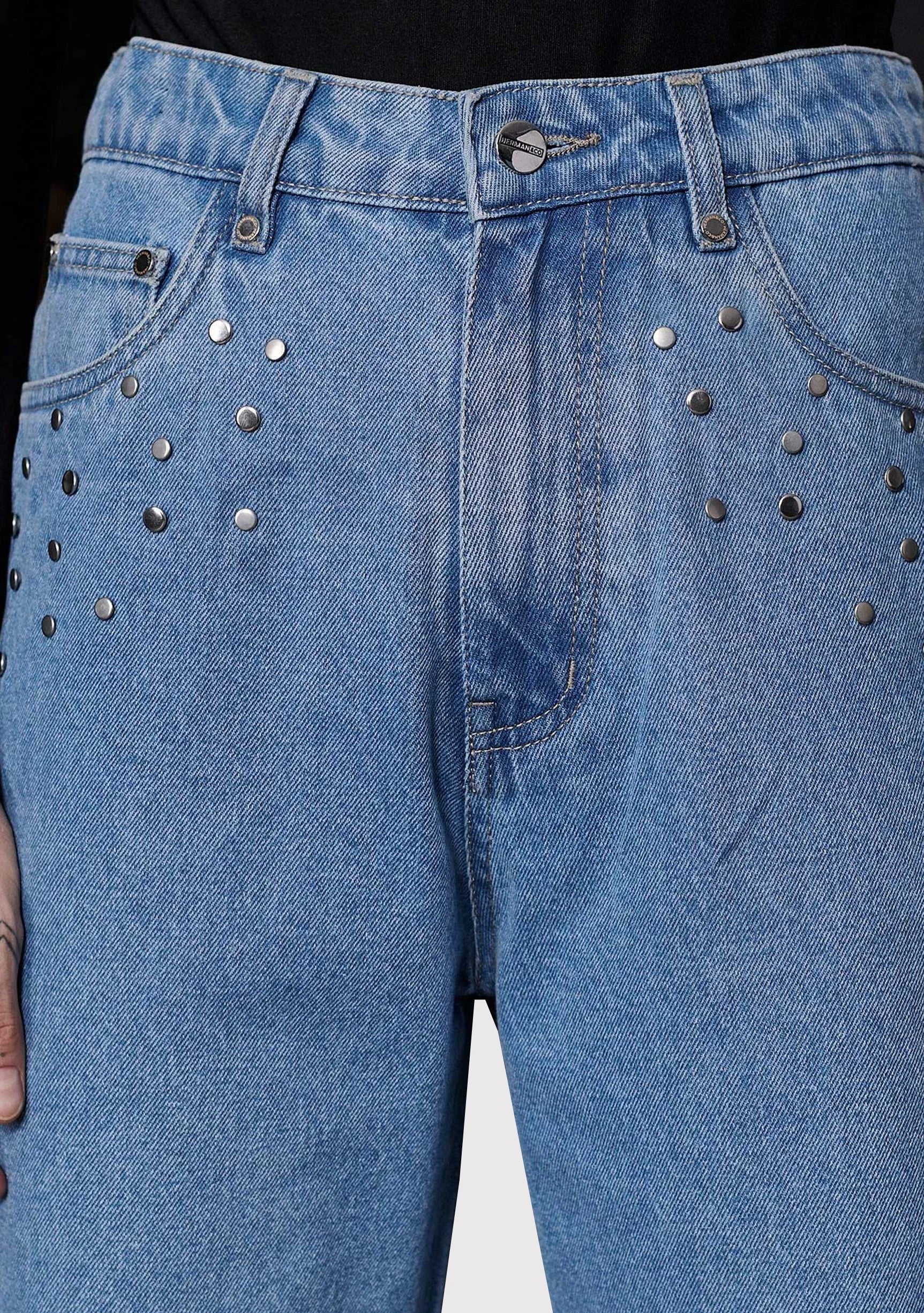 Close up of the high waist and silver studded embellishments around the front pockets on light wash denim.