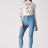 A model styled in the high-waisted blue skinny jeans with a printed top.