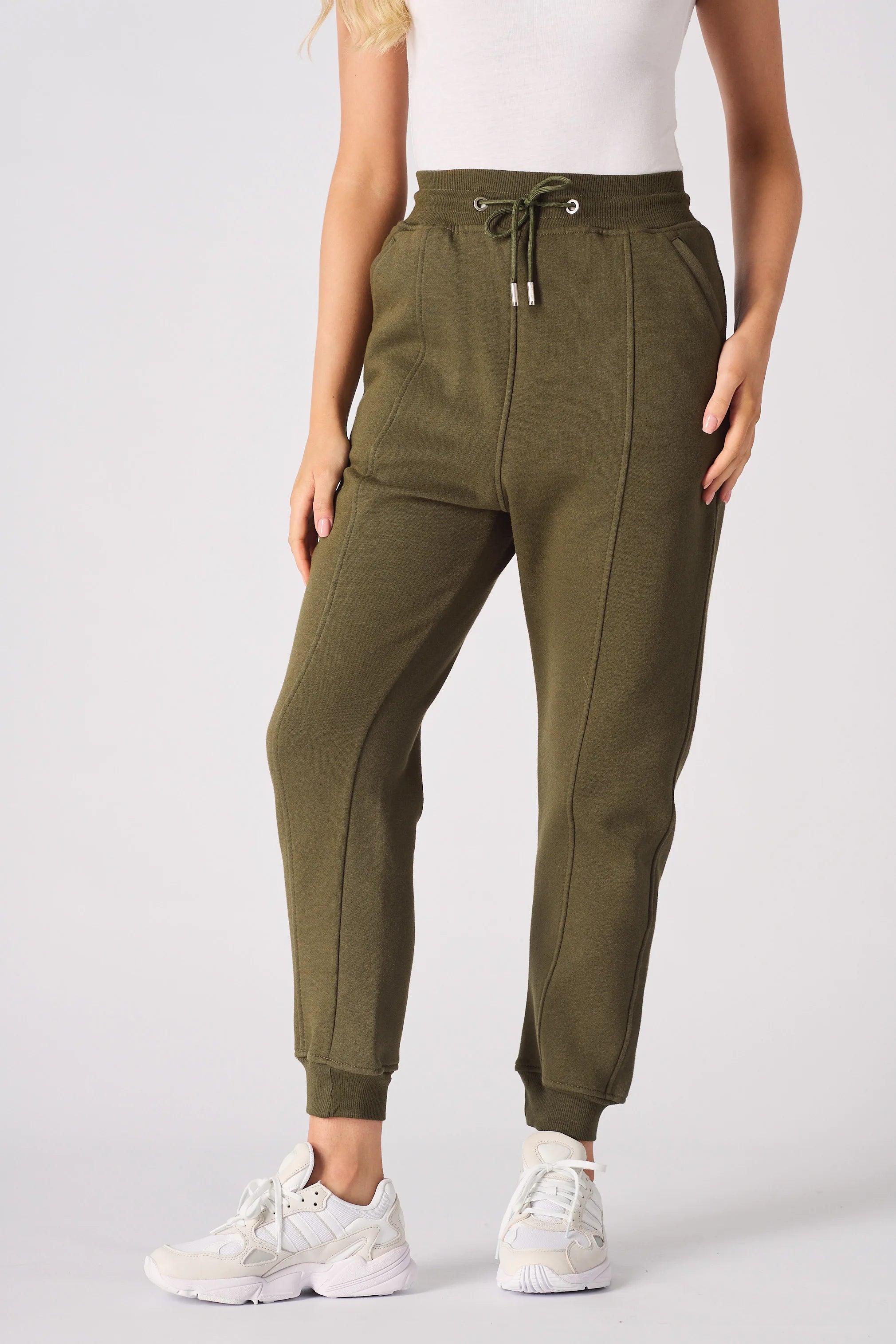 A woman wearing tapered khaki joggers in a full front shot.