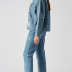 Back and side angle of mid wash tattoo print denim jacket showing sleeve and back embroidery - women’s oversized set with celestial and floral designs on cargo pants