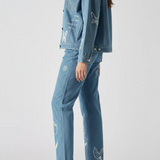 Back and side angle of mid wash tattoo print denim jacket showing sleeve and back embroidery - women’s oversized set with celestial and floral designs on cargo pants