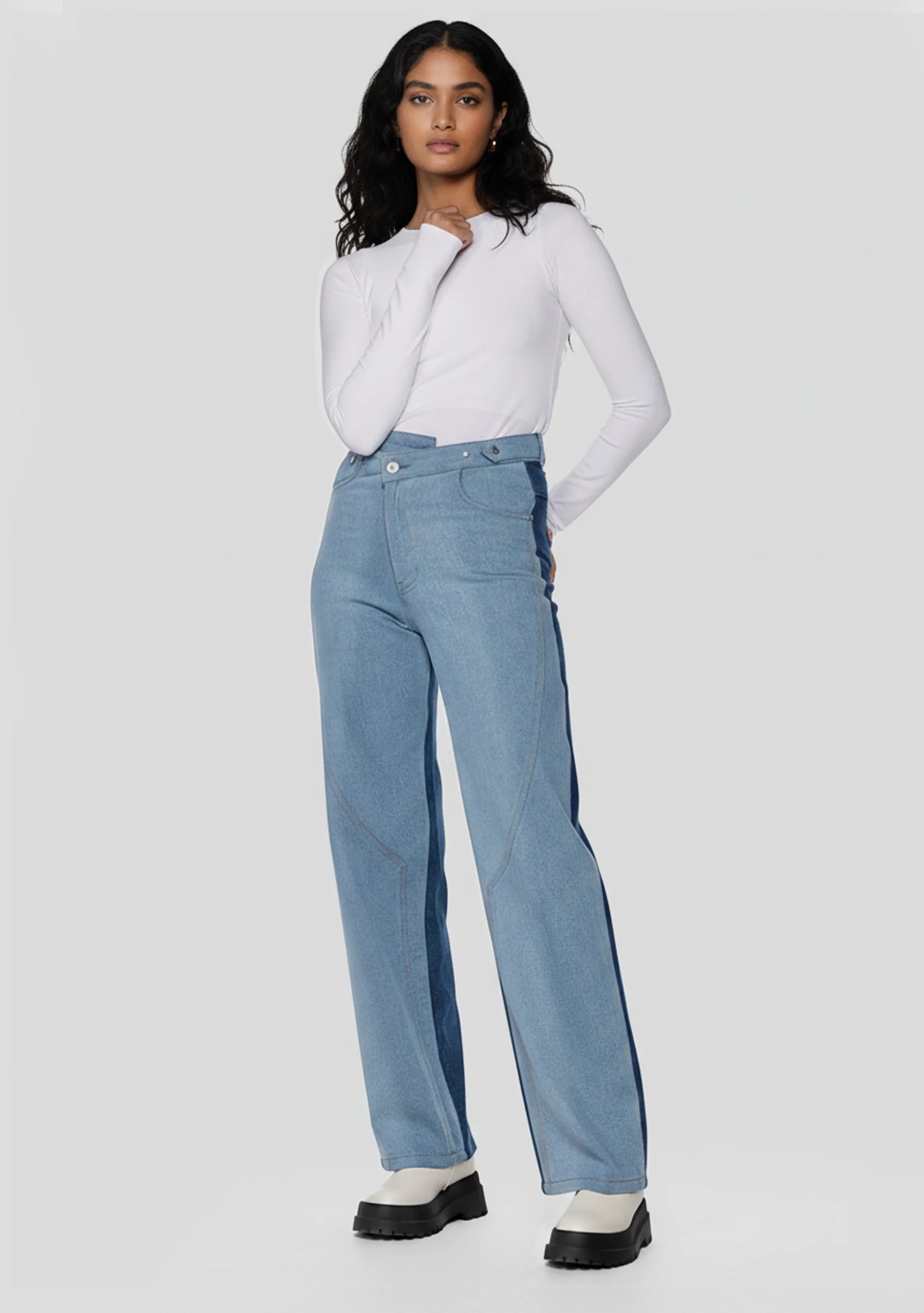 Model wearing high-waisted two-tone wide leg jeans with unique front seam details