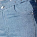 Close up of the curved front seam and side pockets on light blue denim jeans