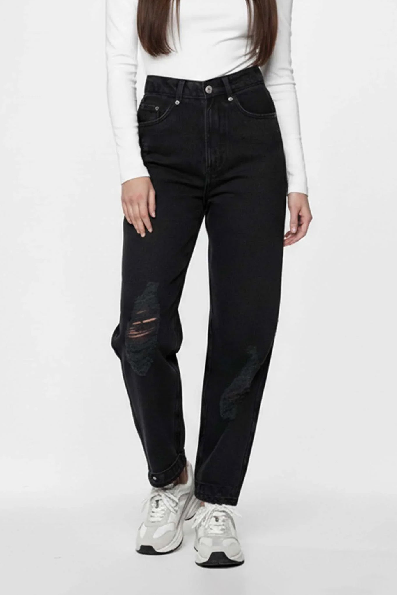 Person wearing black jeans and white sneakers on a white background
