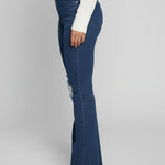 Person wearing blue flared jeans on a plain background