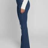 Person wearing blue flared jeans on a plain background