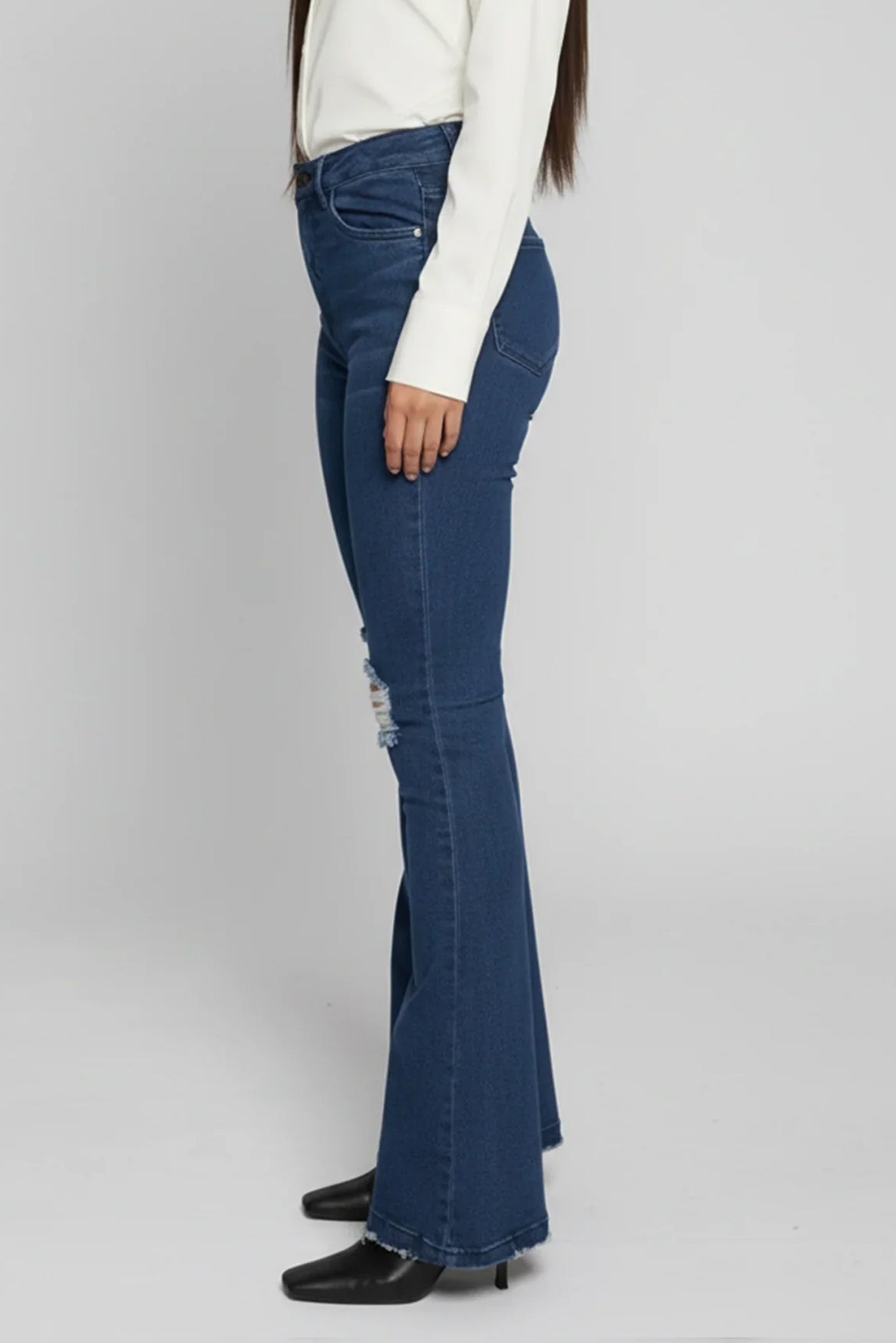 Person wearing blue flared jeans on a plain background
