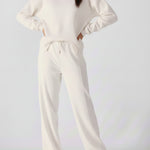 A woman posing with hands on hips wearing a white cotton jumper