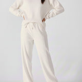 A woman posing with hands on hips wearing a white cotton jumper