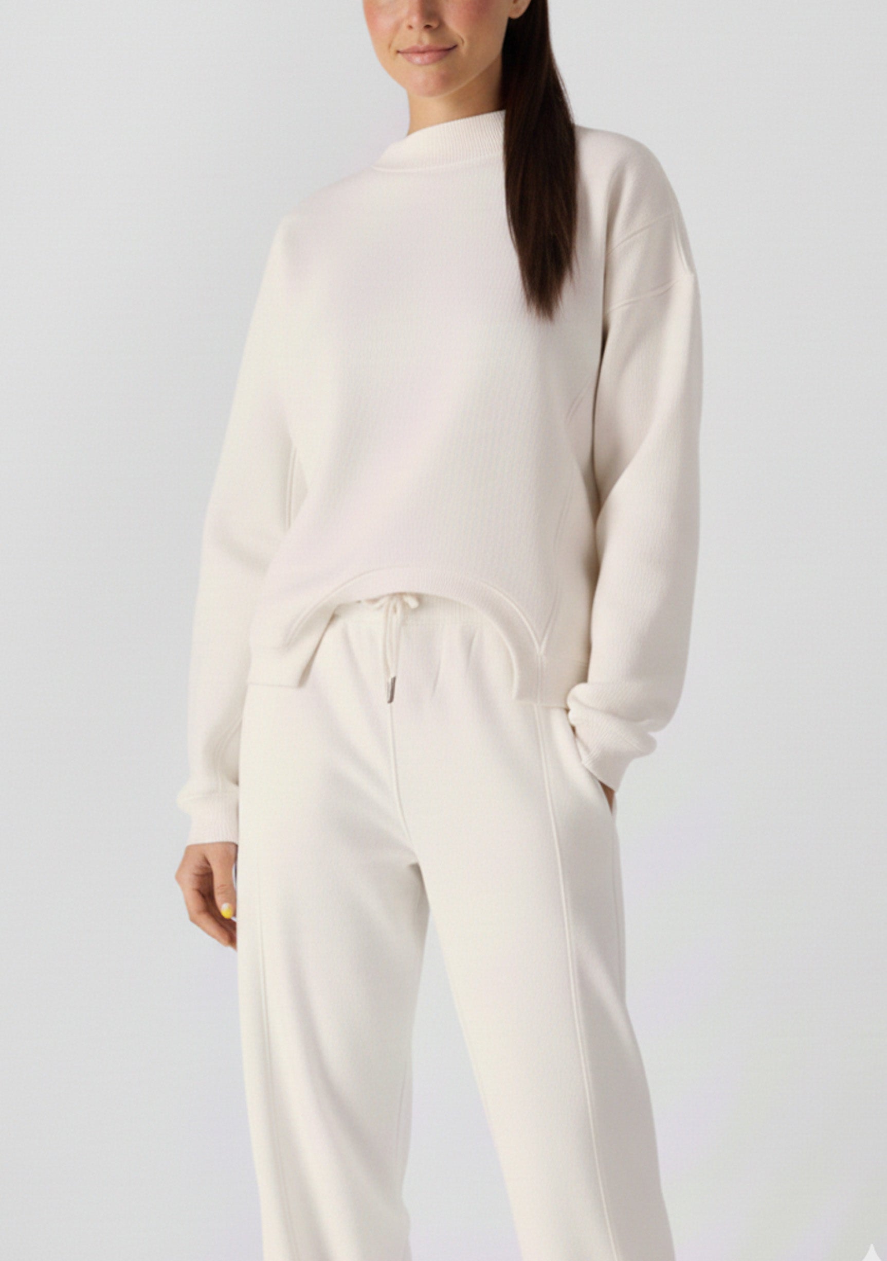 Front view of a woman wearing a white cotton jumper and matching joggers