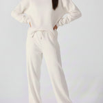 Full front view of a woman styling a cropped white cotton jumper with joggers