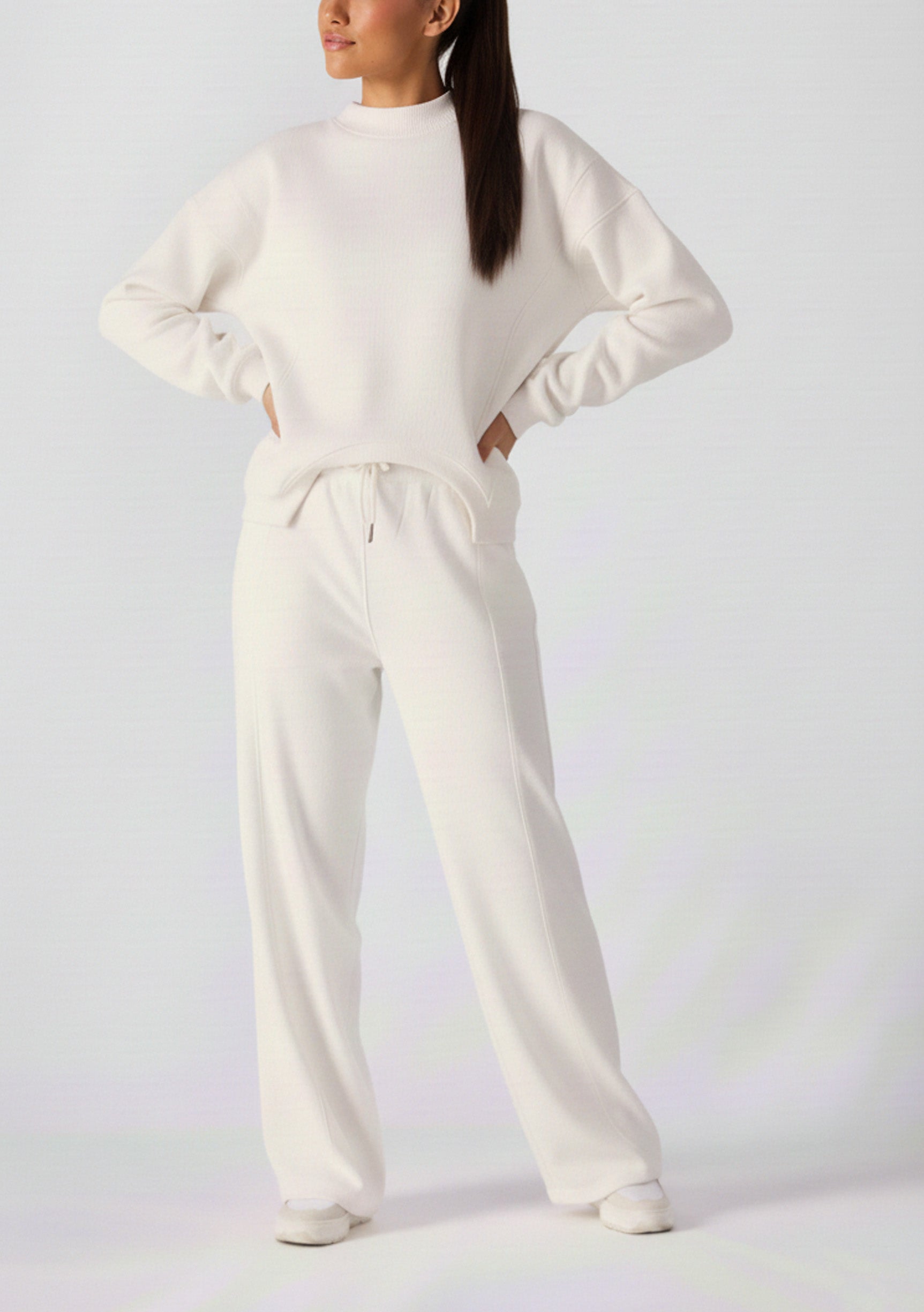 Full front view of a woman styling a cropped white cotton jumper with joggers