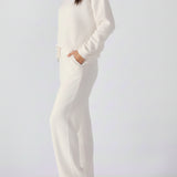 Side view of a woman wearing a white cotton jumper with a panelled design