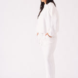 A side view of an oversized white crew neck jumper for women styled with a casual cap