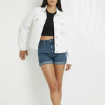 Women wearing white denim trucker jacket leaning against wall - relaxed casual streetwear style